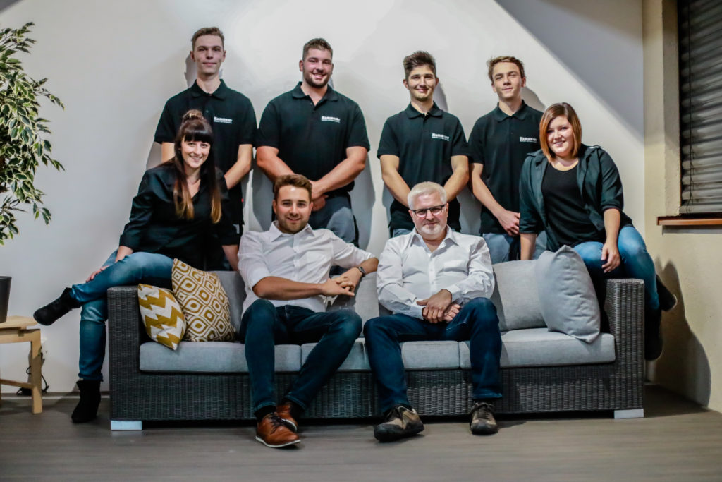 8-Personen-Maenner-und-Frauen-posieren-auf-einem-Sofa-fuer-ein-Mitarbeiter-Bild